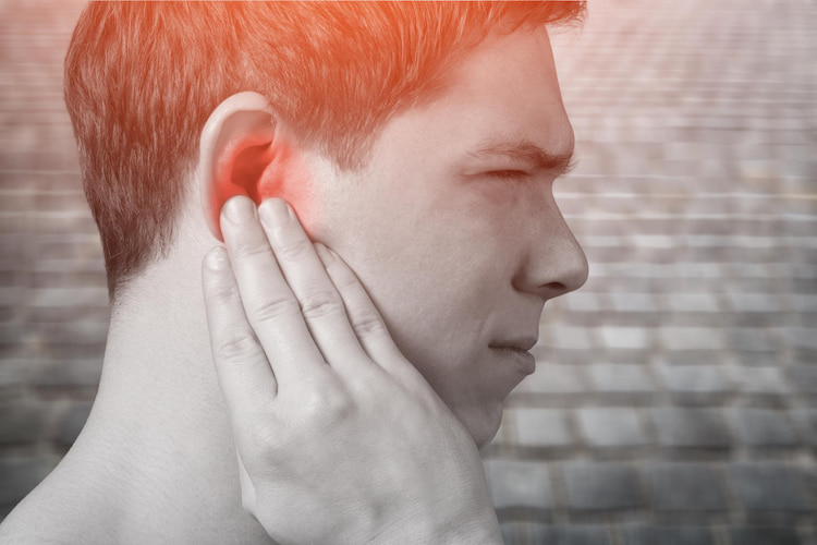 a man is irritated by tooth and ear pain and holding his hand on his ear.